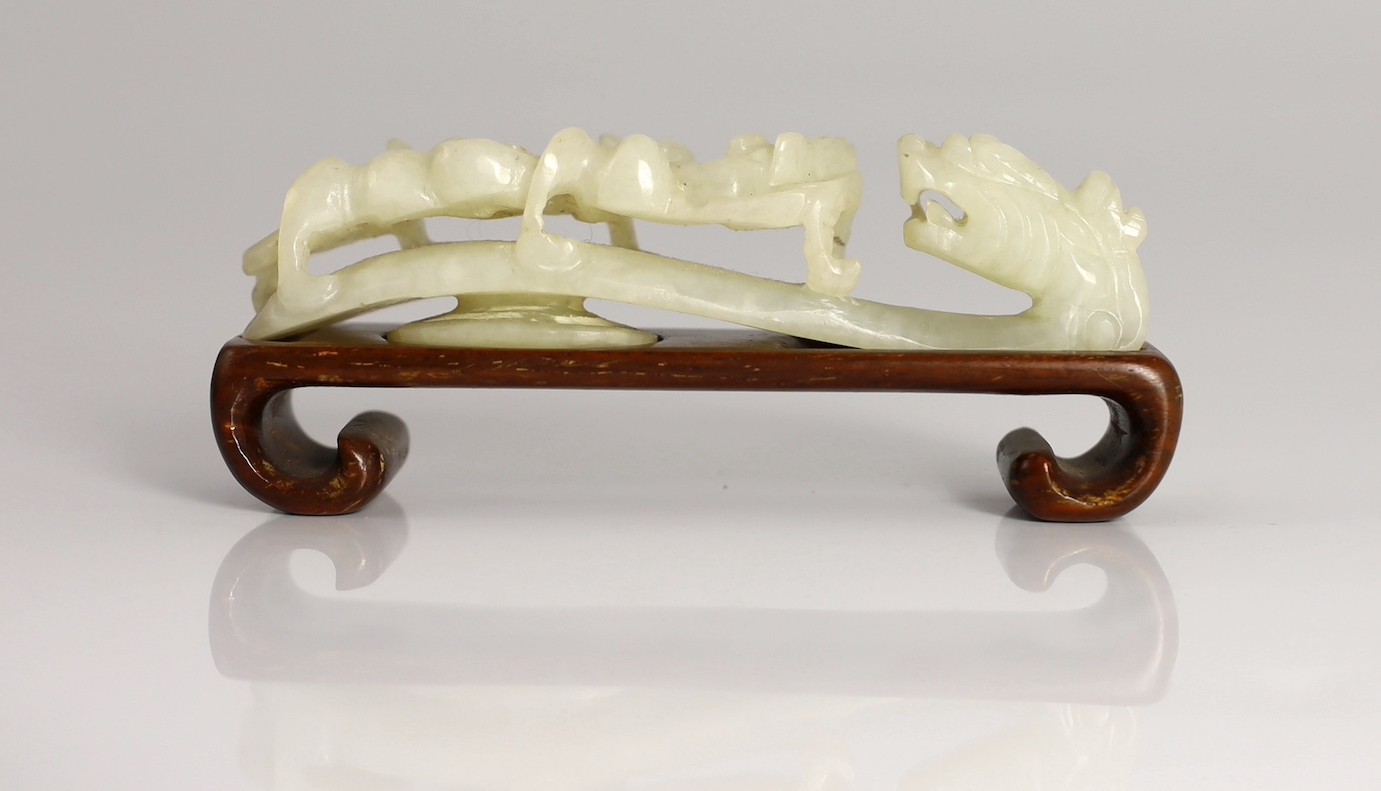 A Chinese white jade ‘dragon’ belt hook, 19th century, 9.4cm long, wood stand